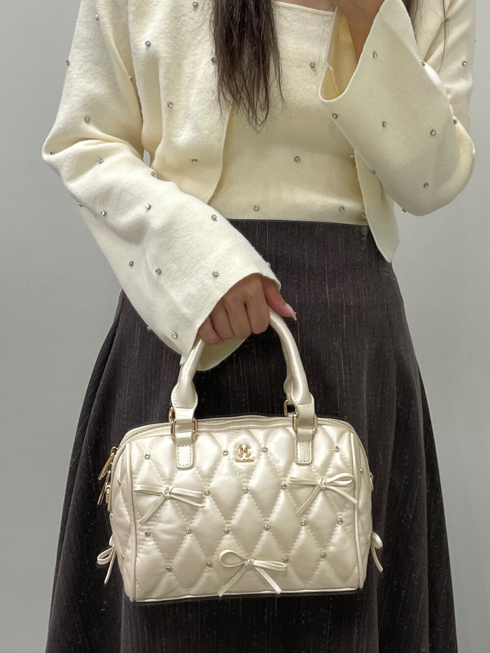 ホワイト系のカーディガン/ボレロ、ホワイト系のキャミソール、ブラウン系のスカートを着用したレディースの秋コーディネートの6枚目の写真