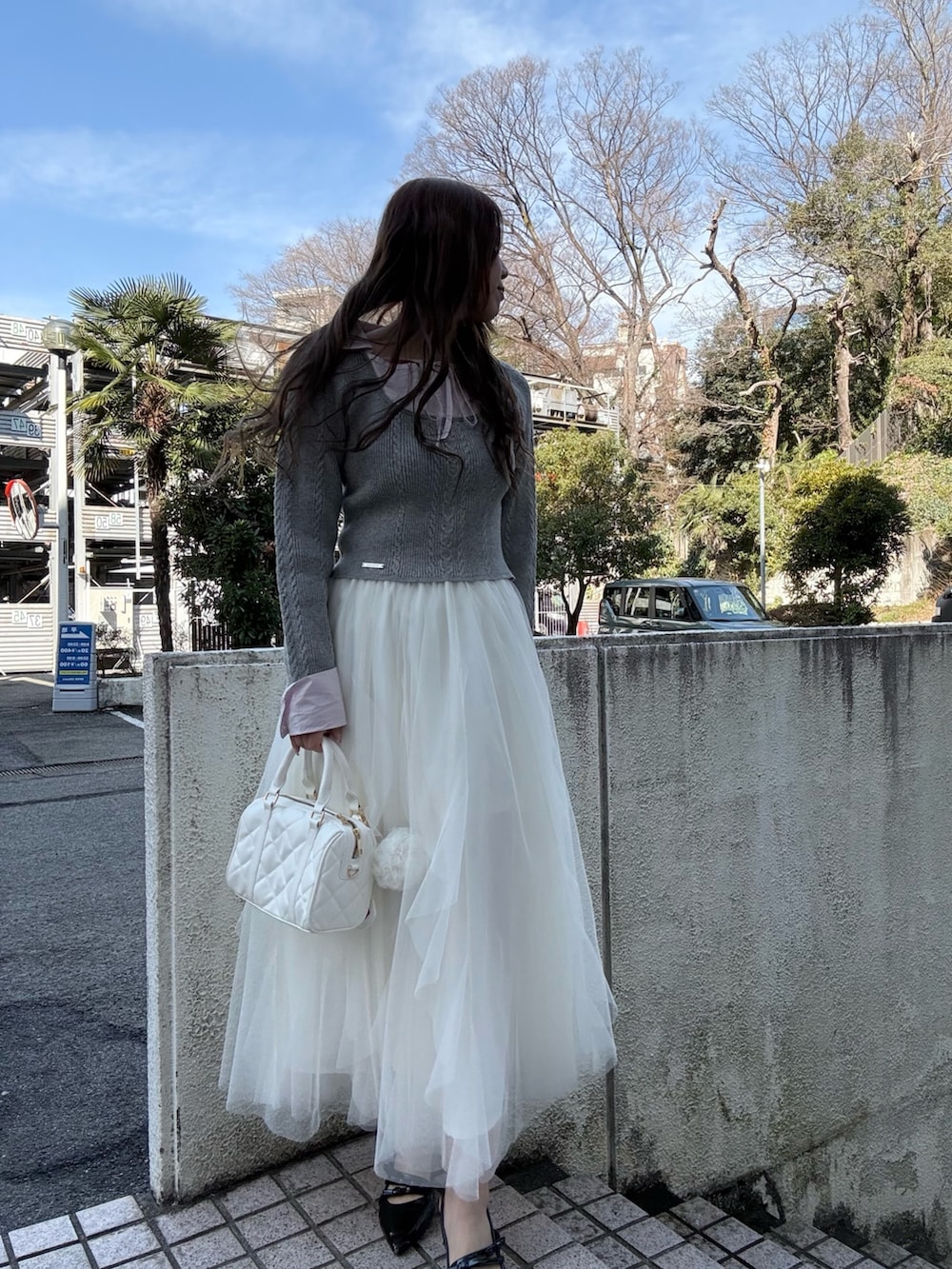 グレー系のニット/セーター、ホワイト系のスカート、ホワイト系のボストンバッグを着用したレディースの冬コーディネートの3枚目の写真