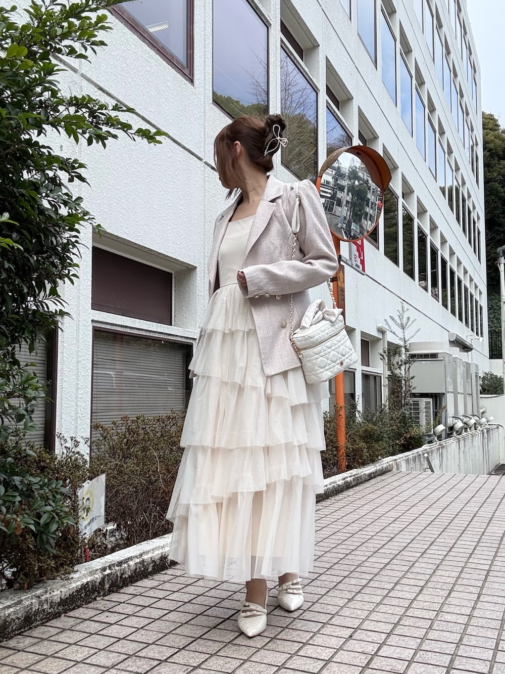 ピンク系のテーラードジャケット、ホワイト系のワンピース、ホワイト系のショルダーバッグを着用したレディースの冬コーディネートの2枚目の写真