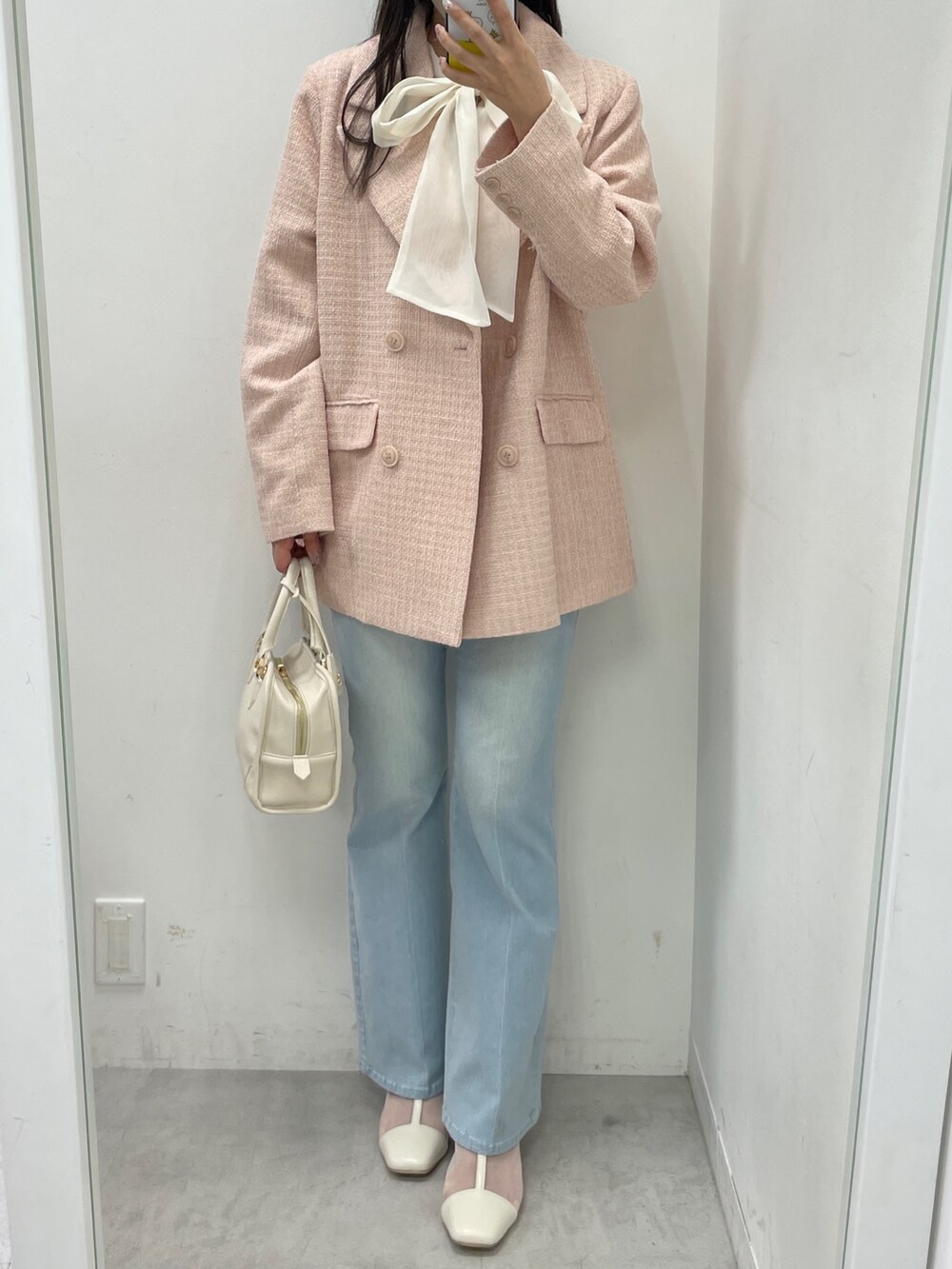 ピンク系のテーラードジャケット、ブルー系のデニムパンツ、ホワイト系のブーツを着用したレディースの冬コーディネートの2枚目の写真