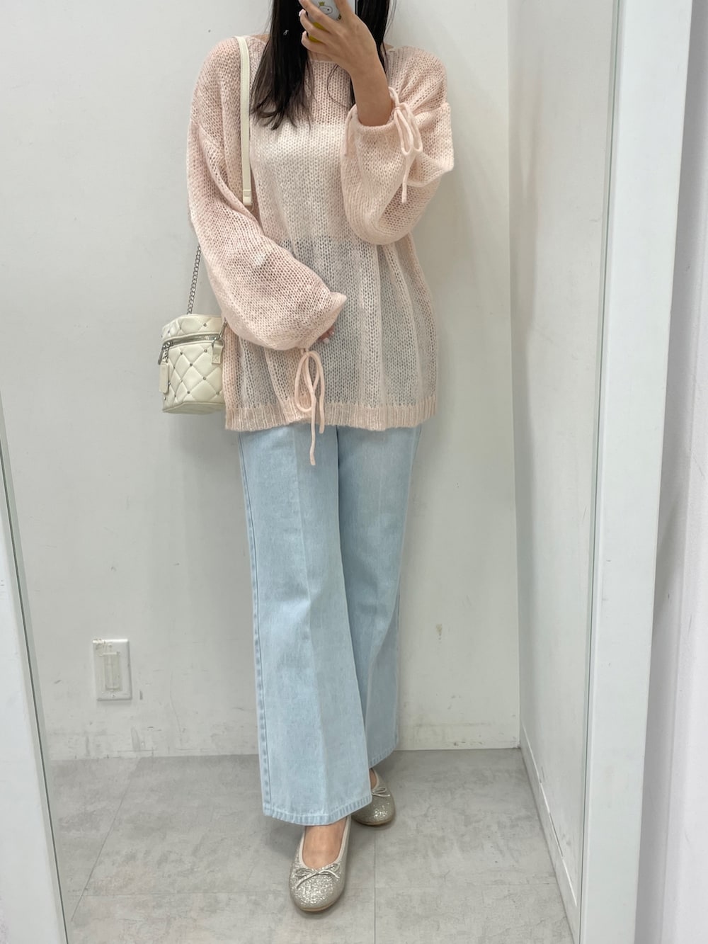 ピンク系のニット/セーター、ブルー系のデニムパンツ、ブラック系のショルダーバッグを着用したレディースの冬コーディネートの3枚目の写真