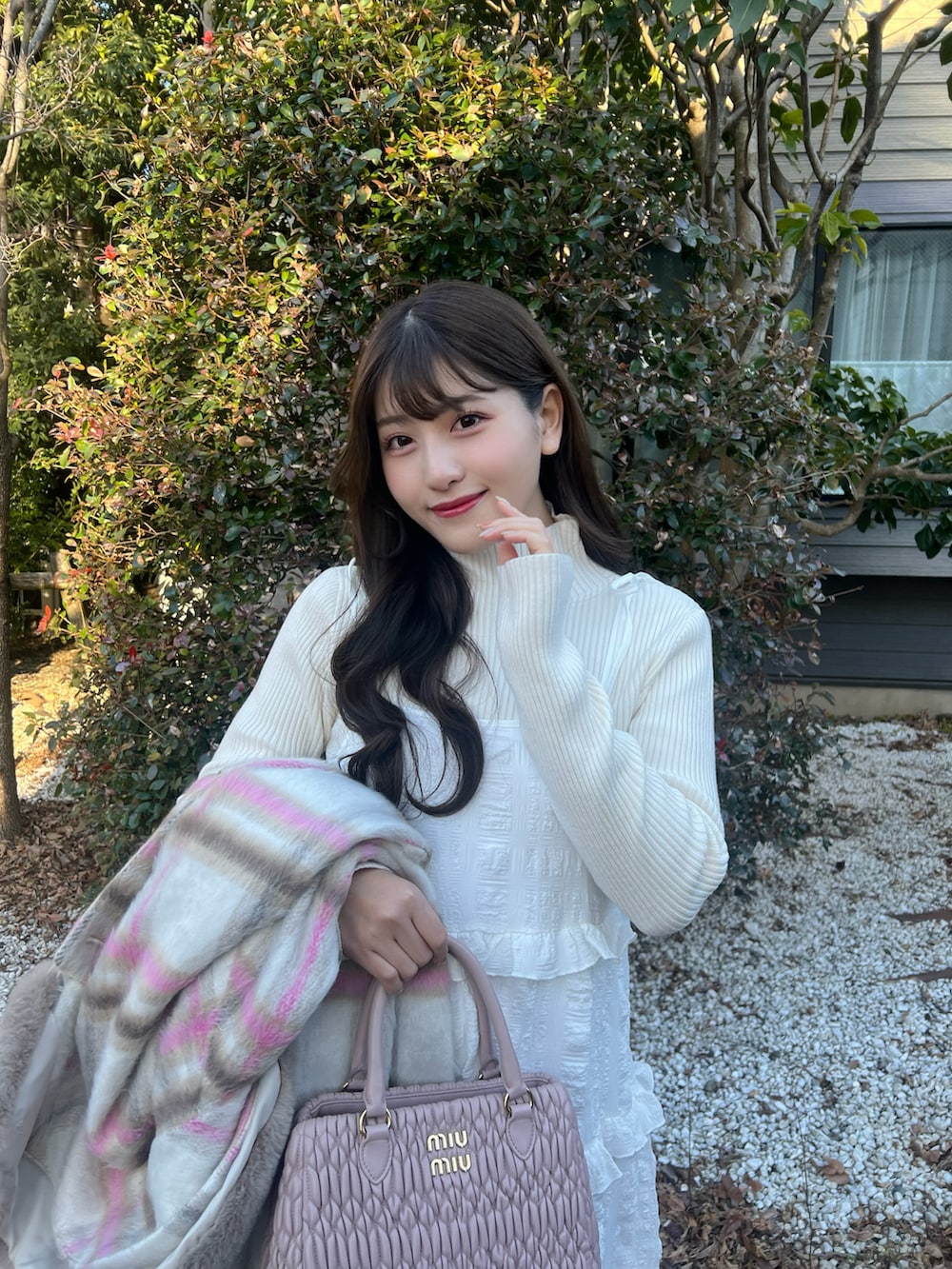 ホワイト系のワンピース、ピンク系のステンカラーコート、ピンク系のバッグを着用したレディースの冬コーディネートの4枚目の写真