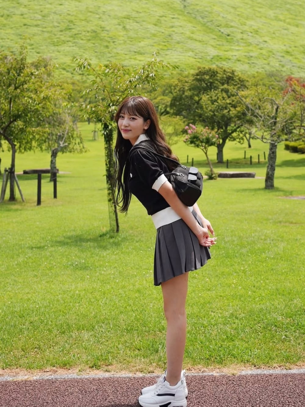 ブラック系のショルダーバッグ、ブラック系のニット/セーター、グレー系のスカートを着用したレディースの夏コーディネートの3枚目の写真