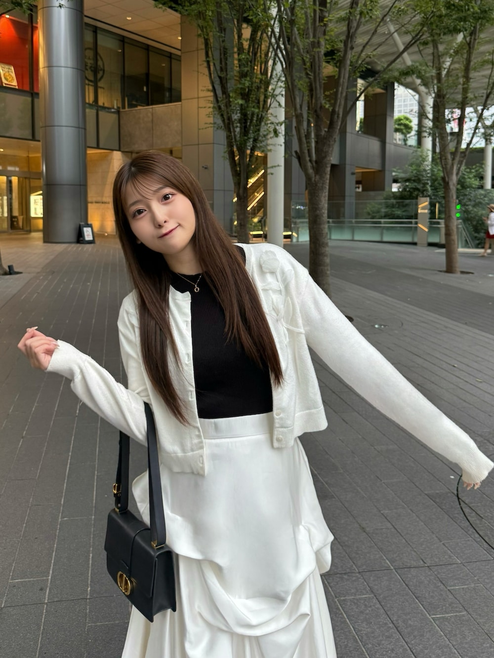 ブラック系のパンプス、ホワイト系のスカート、ブラック系のショルダーバッグを着用したレディースの秋コーディネートの2枚目の写真