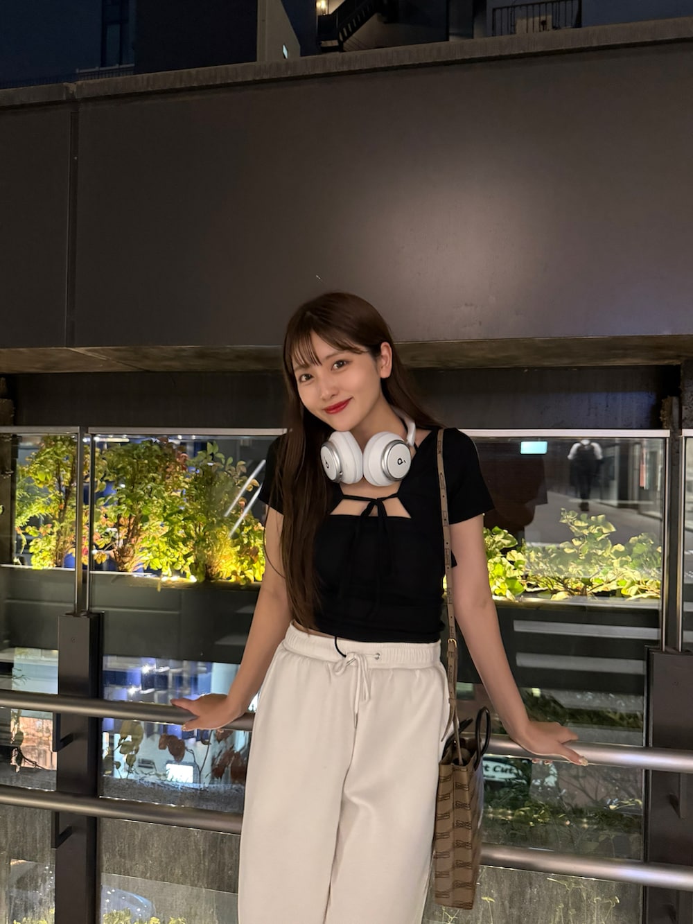 ホワイト系のスウェットパンツ、ブラック系のアンサンブル、ブラウン系のバッグを着用したレディースの秋コーディネートの2枚目の写真