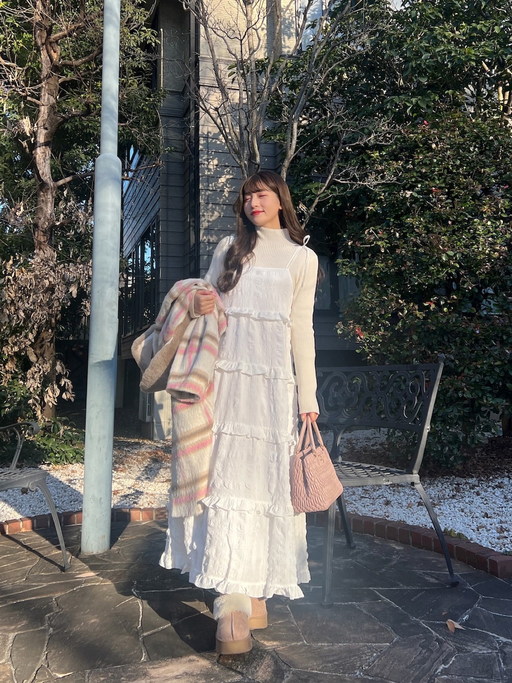 ホワイト系のワンピース、ピンク系のステンカラーコート、ピンク系のバッグを着用したレディースの冬コーディネートの3枚目の写真