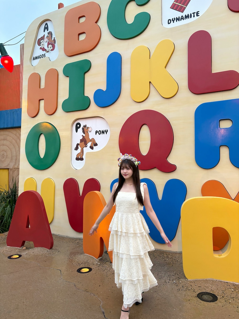 イエロー系のワンピース、ベージュ系のバッグ、ホワイト系のパンプスを着用したレディースの夏コーディネートの4枚目の写真