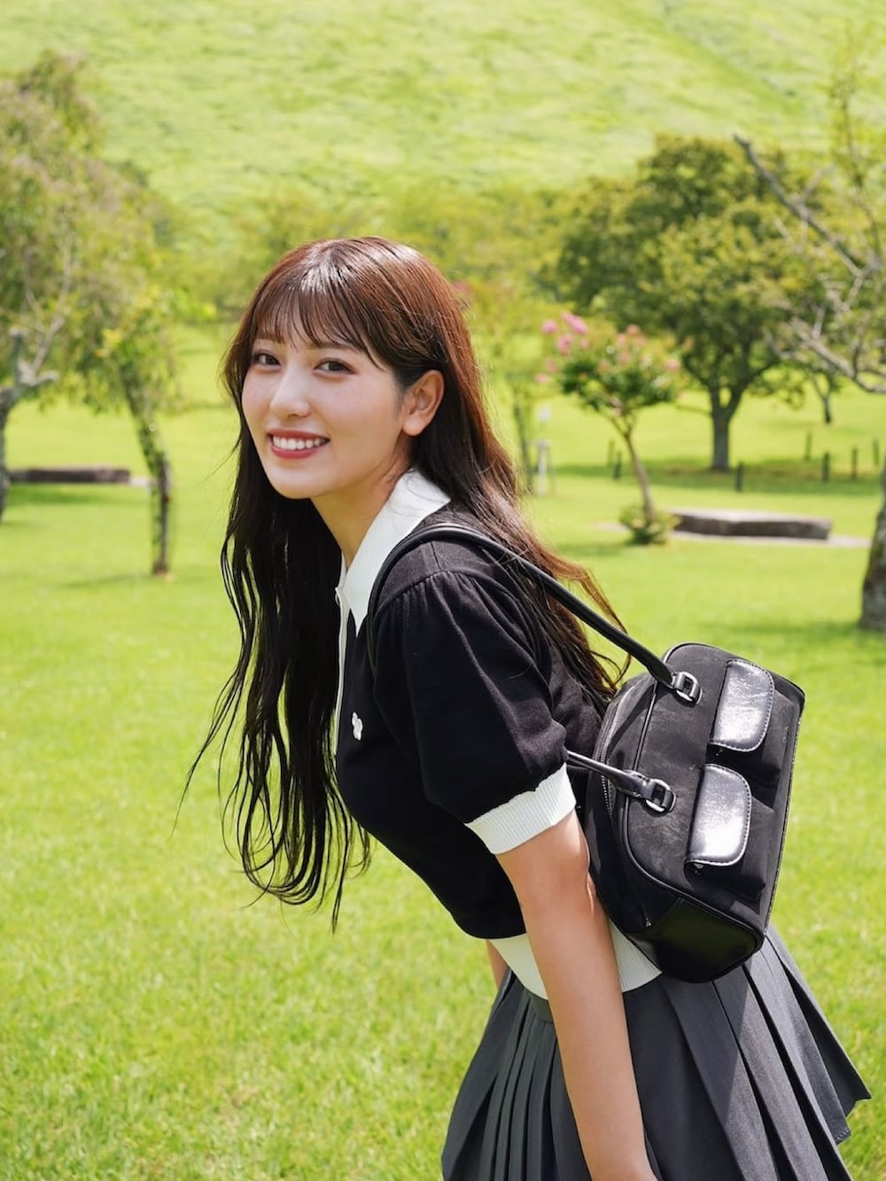 ブラック系のショルダーバッグ、ブラック系のニット/セーター、グレー系のスカートを着用したレディースの夏コーディネートの4枚目の写真