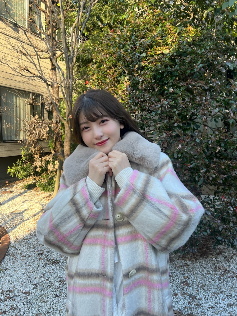 ホワイト系のワンピース、ピンク系のステンカラーコート、ピンク系のバッグを着用したレディースの冬コーディネートの2枚目の写真