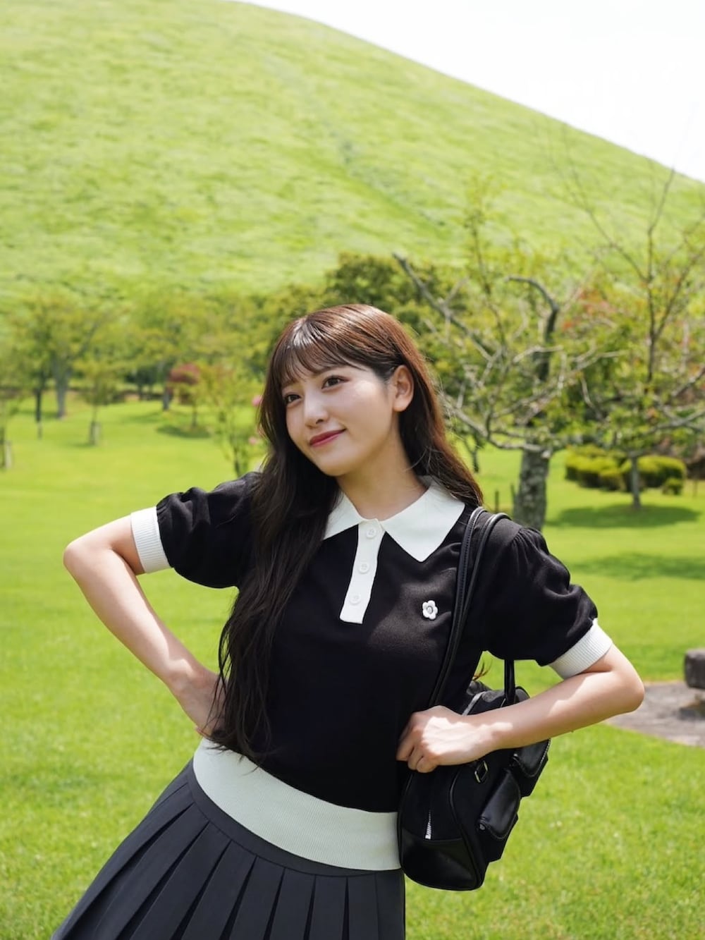 ブラック系のショルダーバッグ、ブラック系のニット/セーター、グレー系のスカートを着用したレディースの夏コーディネートの2枚目の写真