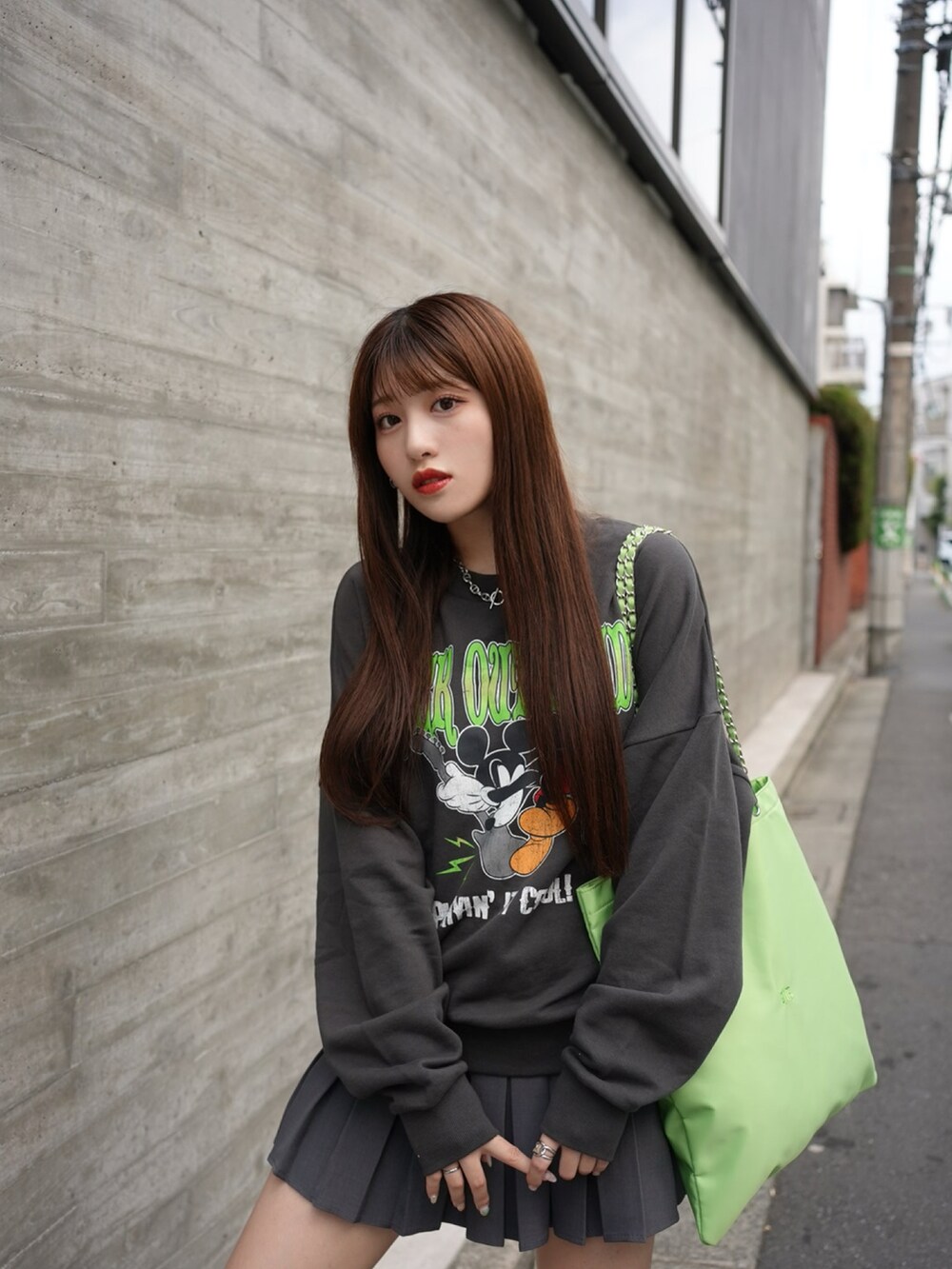 ブラック系のスウェット、グリーン系のトートバッグ、グレー系のスカートを着用したレディースの秋コーディネートの2枚目の写真