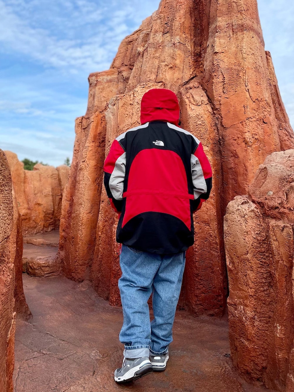 ブルー系のデニムパンツ、グレー系のスニーカー、レッド系のマウンテンパーカーを着用したメンズの冬コーディネートの3枚目の写真