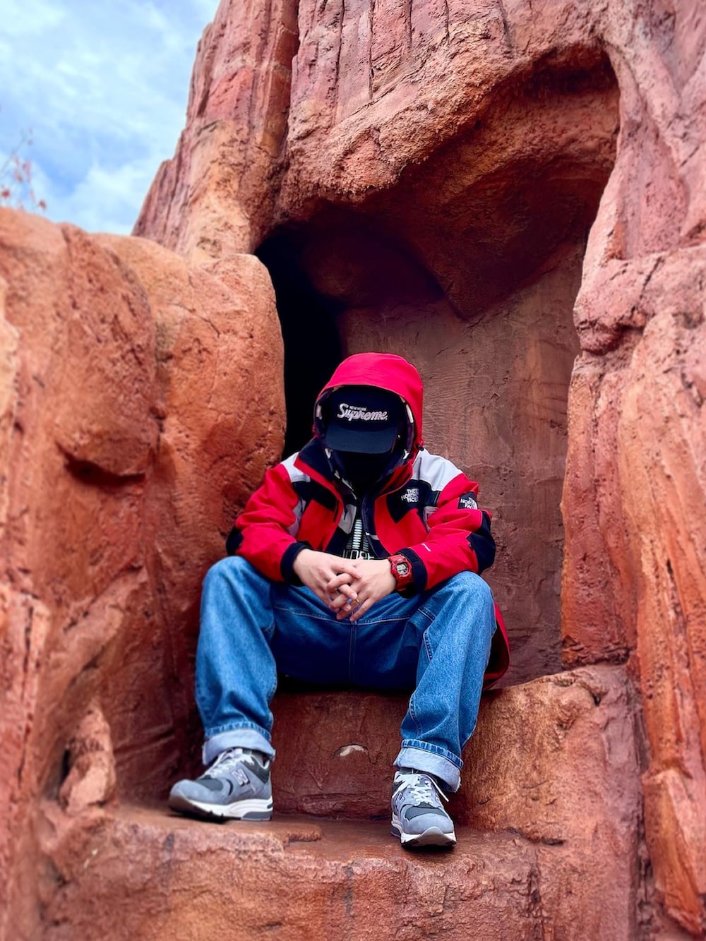 ブルー系のデニムパンツ、グレー系のスニーカー、レッド系のマウンテンパーカーを着用したメンズの冬コーディネートの4枚目の写真