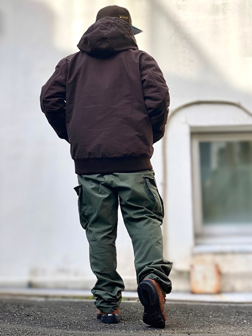 ブラック系のパーカー、ブラウン系のその他アウター、グリーン系のカーゴパンツを着用したメンズの冬コーディネートの2枚目の写真
