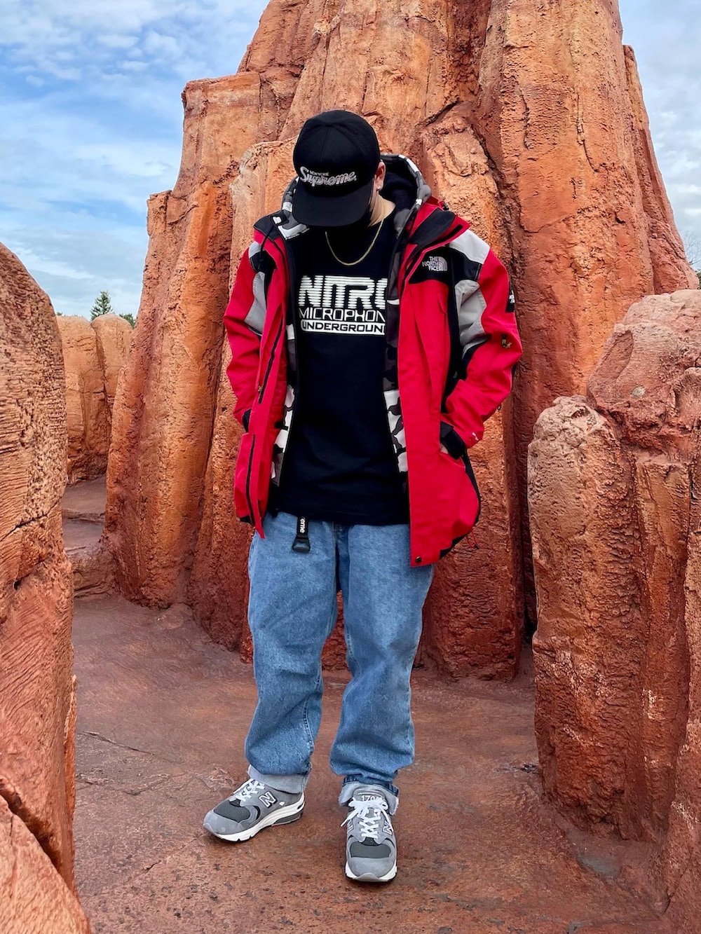 ブルー系のデニムパンツ、グレー系のスニーカー、レッド系のマウンテンパーカーを着用したメンズの冬コーディネートの2枚目の写真