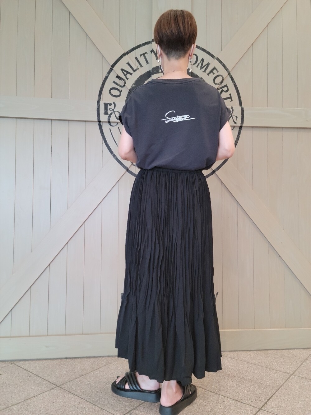 ブラック系のTシャツ/カットソー、ブラック系のスカート、ブラック系のサンダルを着用したレディースの夏コーディネートの2枚目の写真