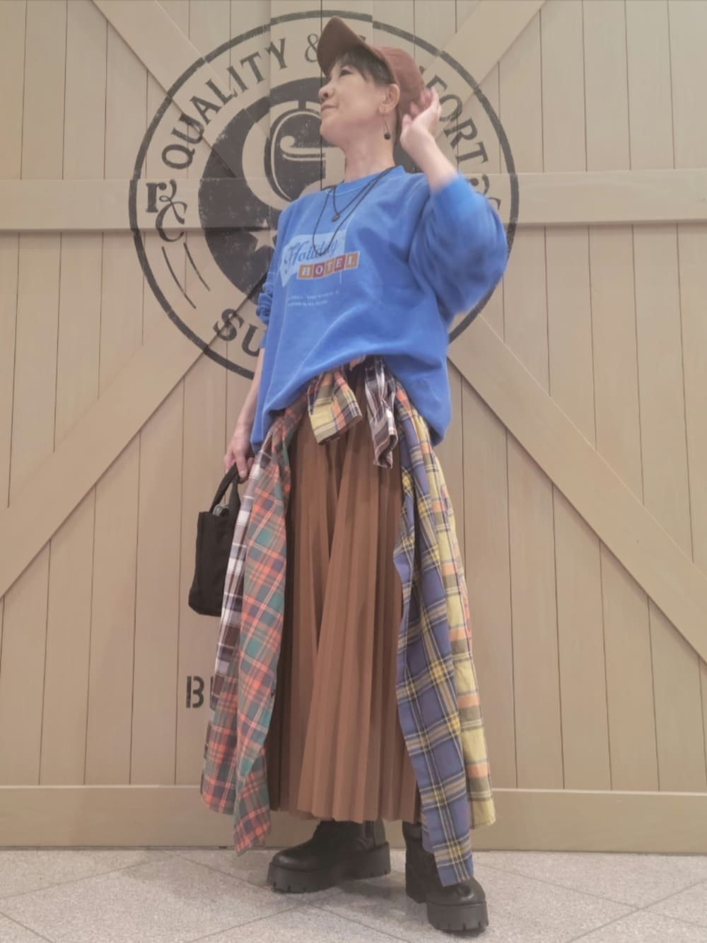 ブルー系のスウェット、グリーン系のシャツワンピース、ブラウン系のスカートを着用したレディースの春コーディネートの3枚目の写真