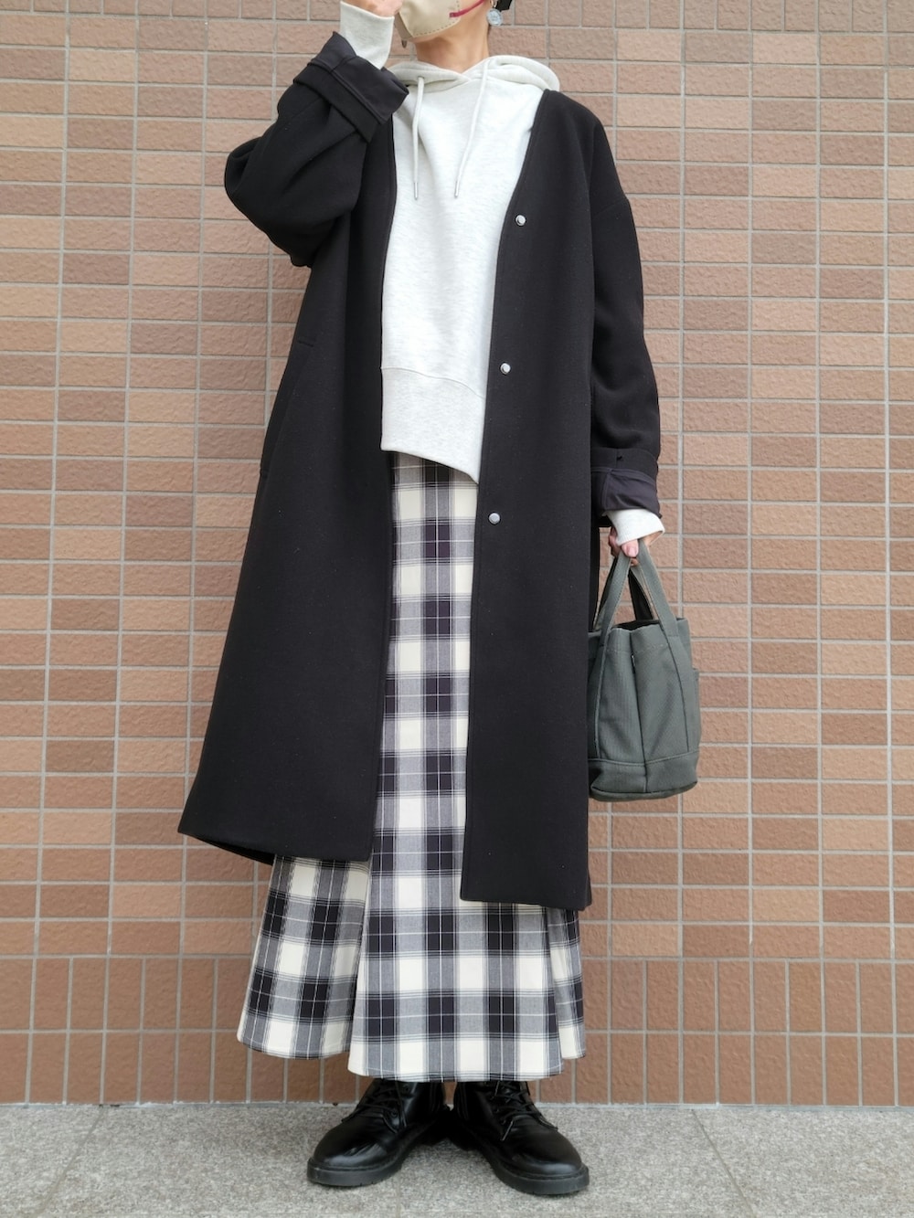 ホワイト系のパーカー、ブラック系のスカート、ブラック系のノーカラーコートを着用したレディースの冬コーディネートの2枚目の写真