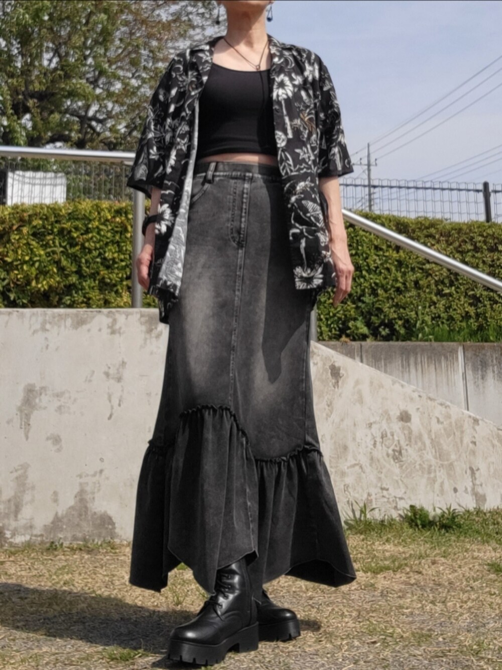 ブラック系のデニムスカート、ブラック系のシャツ/ブラウス、ブラック系のブーツを着用したレディースの春コーディネートの2枚目の写真