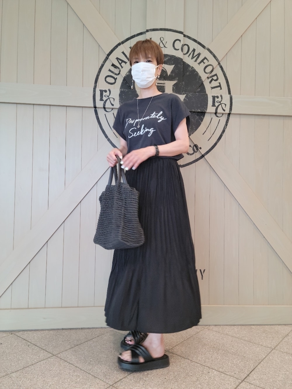 ブラック系のTシャツ/カットソー、ブラック系のスカート、ブラック系のサンダルを着用したレディースの夏コーディネートの3枚目の写真