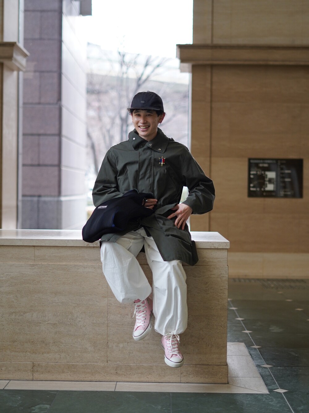 ブラック系のバッグ、ホワイト系のパンツ、ピンク系のスニーカーを着用したメンズの冬コーディネートの2枚目の写真