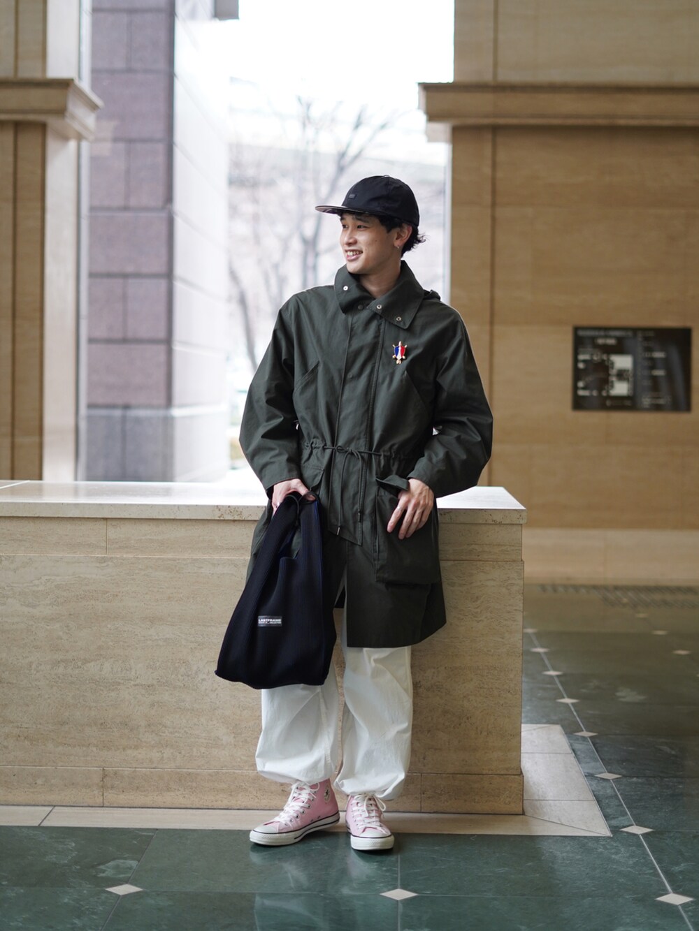 ブラック系のバッグ、ホワイト系のパンツ、ピンク系のスニーカーを着用したメンズの冬コーディネートの3枚目の写真