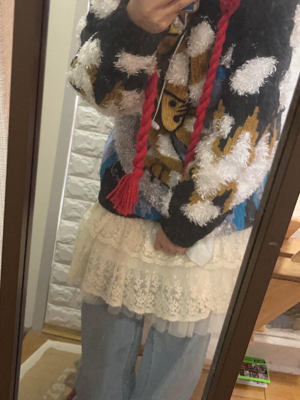 ベージュ系のショルダーバッグ、ブルー系のデニムパンツ、ブラック系のニット/セーターを着用したレディースの冬コーディネートの2枚目の写真