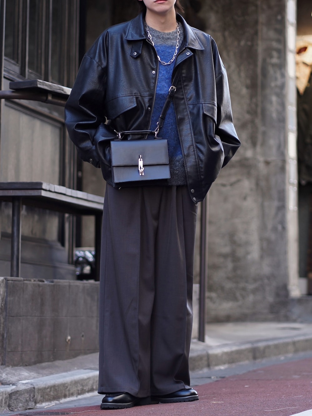 ブラック系のブルゾン、ブルー系のニット/セーター、グレー系のスラックスを着用したメンズの春コーディネートの2枚目の写真