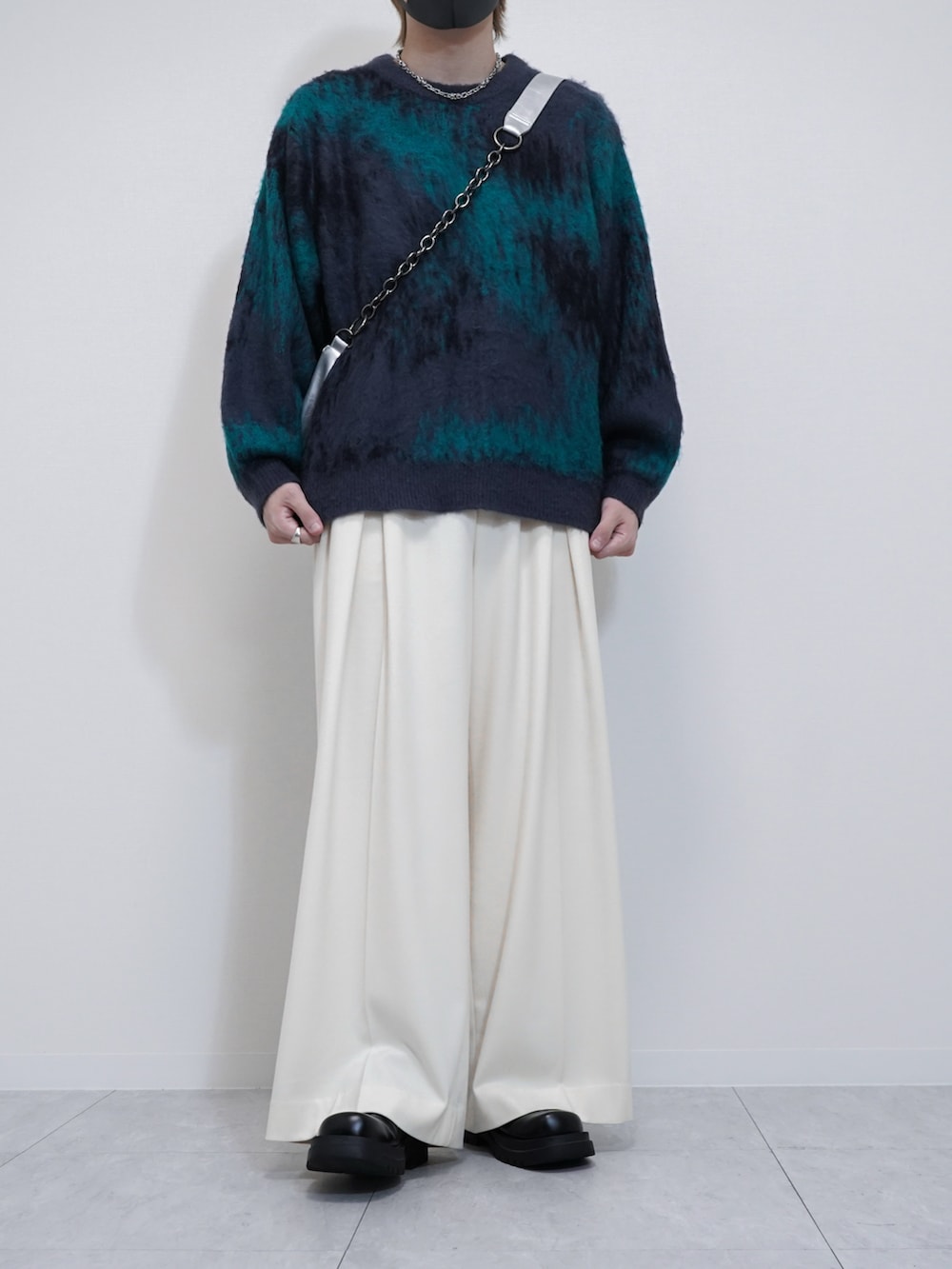 ブルー系のニット/セーター、ブラック系のブルゾン、ホワイト系のスラックスを着用したメンズの秋コーディネートの2枚目の写真