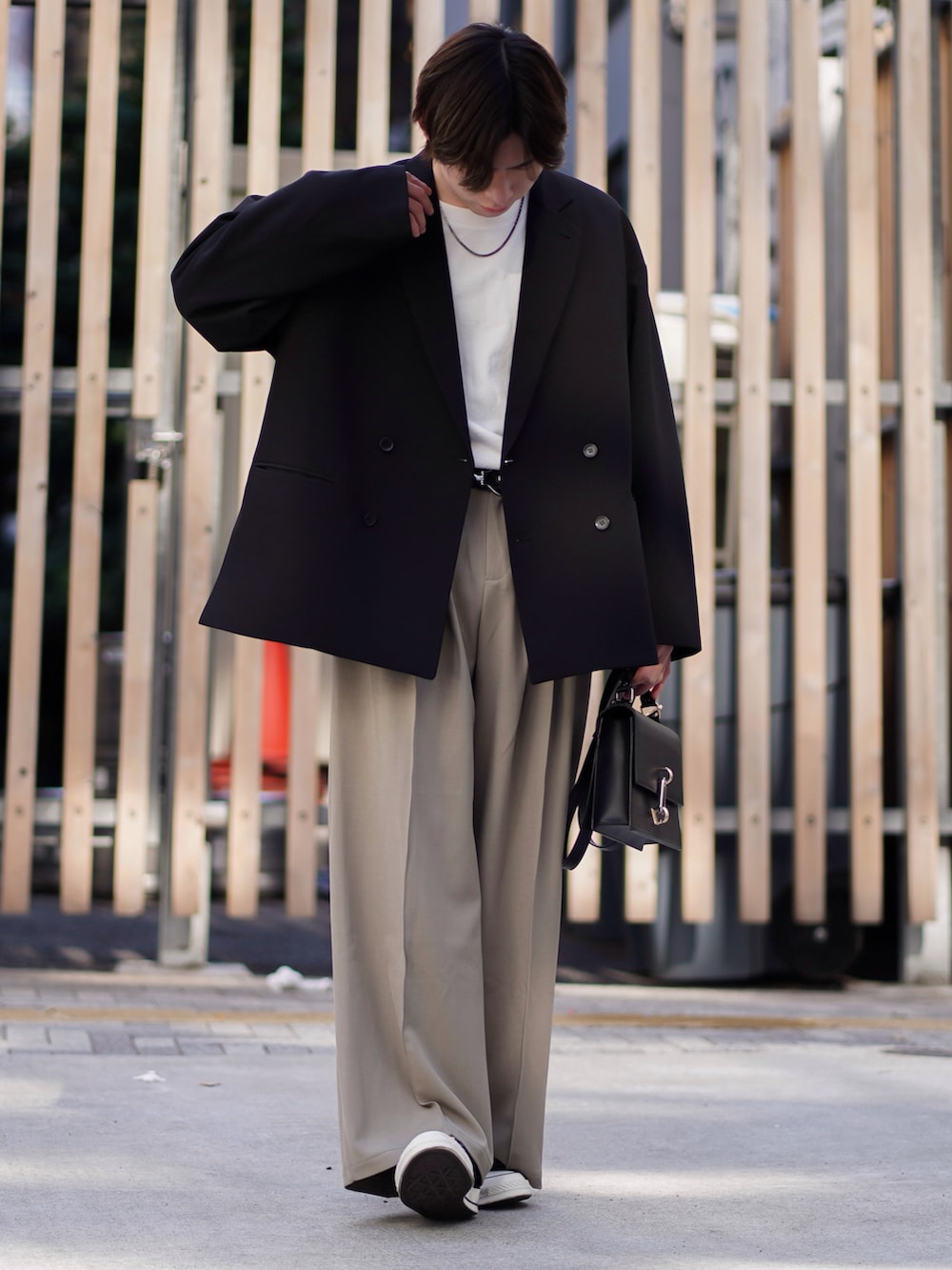 ブラック系のテーラードジャケット、ホワイト系のTシャツ/カットソー、ベージュ系のスラックスを着用したメンズの春コーディネートの2枚目の写真