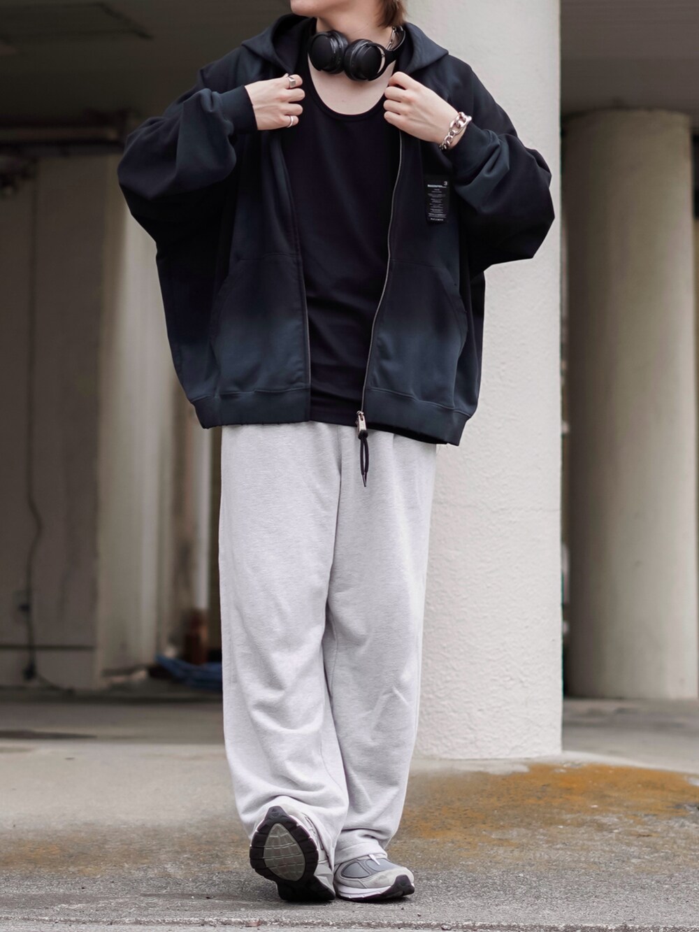 ブラック系のパーカー、ブラック系のタンクトップ、グレー系のスウェットパンツを着用したメンズの春コーディネートの2枚目の写真