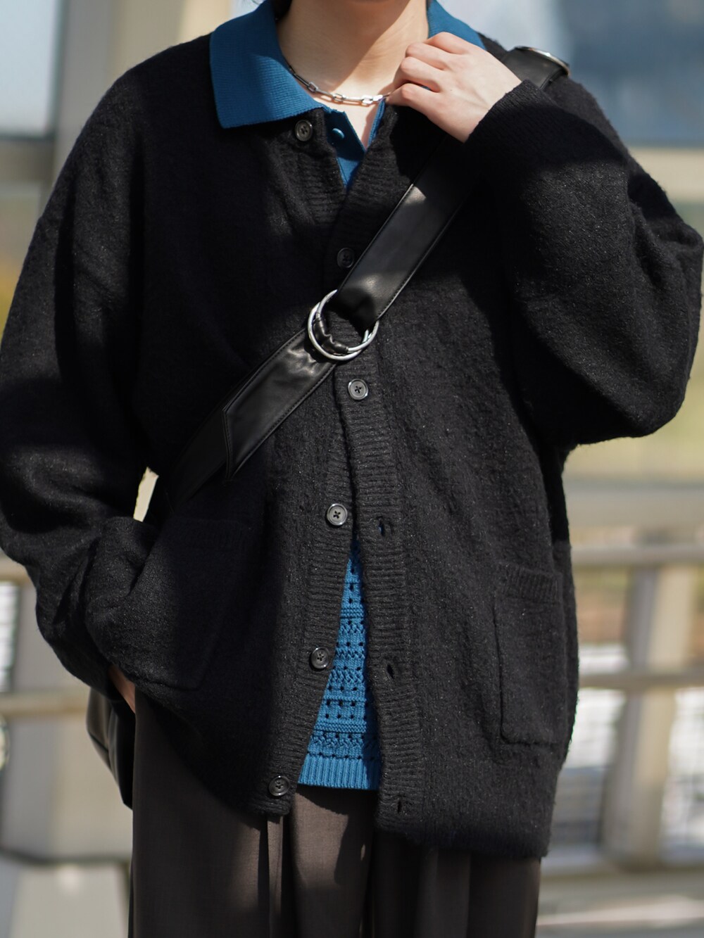 ブラック系のカーディガン/ボレロ、ブルー系のポロシャツ、グレー系のスラックスを着用したメンズの春コーディネートの2枚目の写真