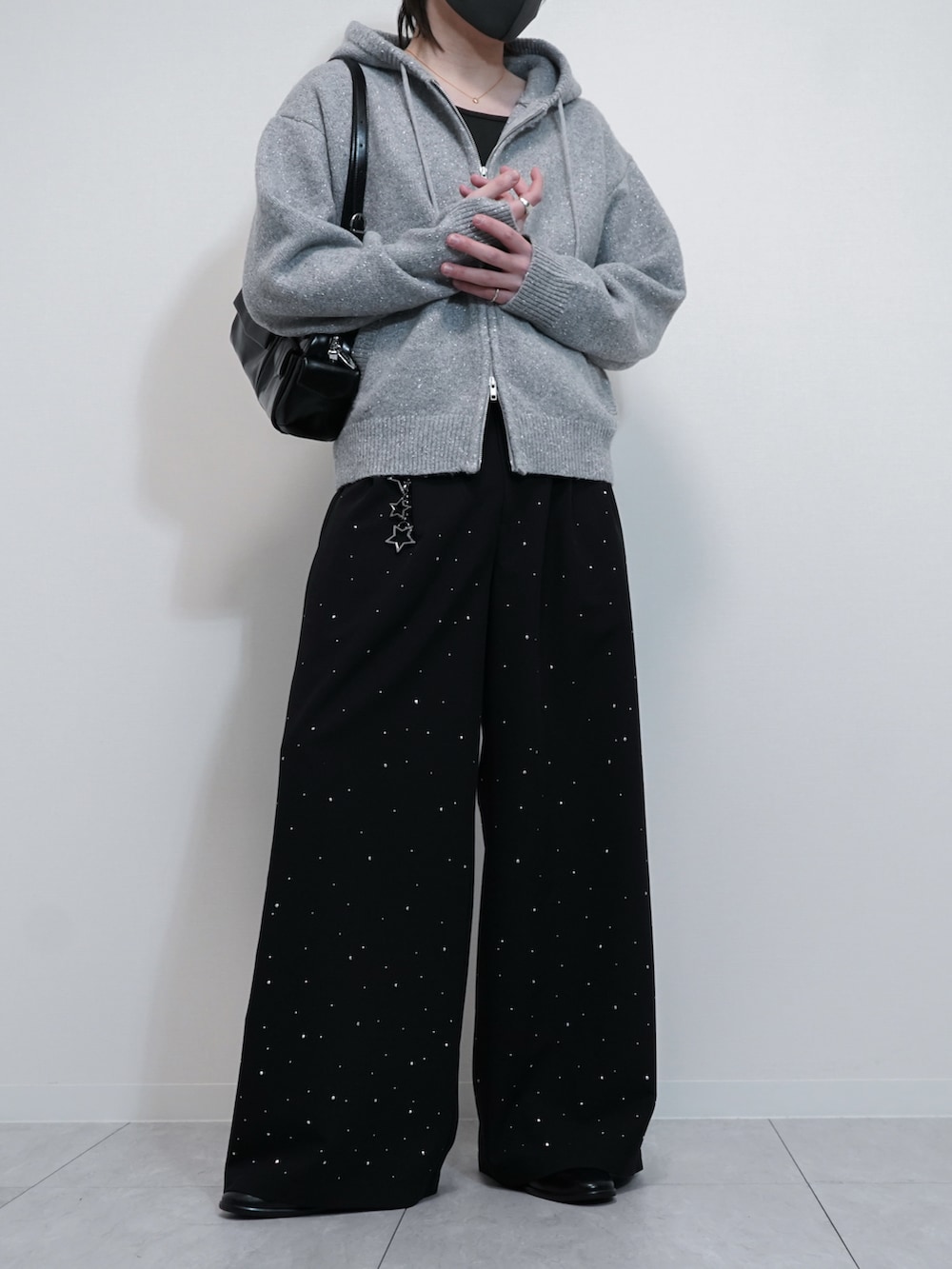 グレー系のパーカー、ブラック系のスラックス、ブラック系のショルダーバッグを着用したメンズの冬コーディネートの2枚目の写真