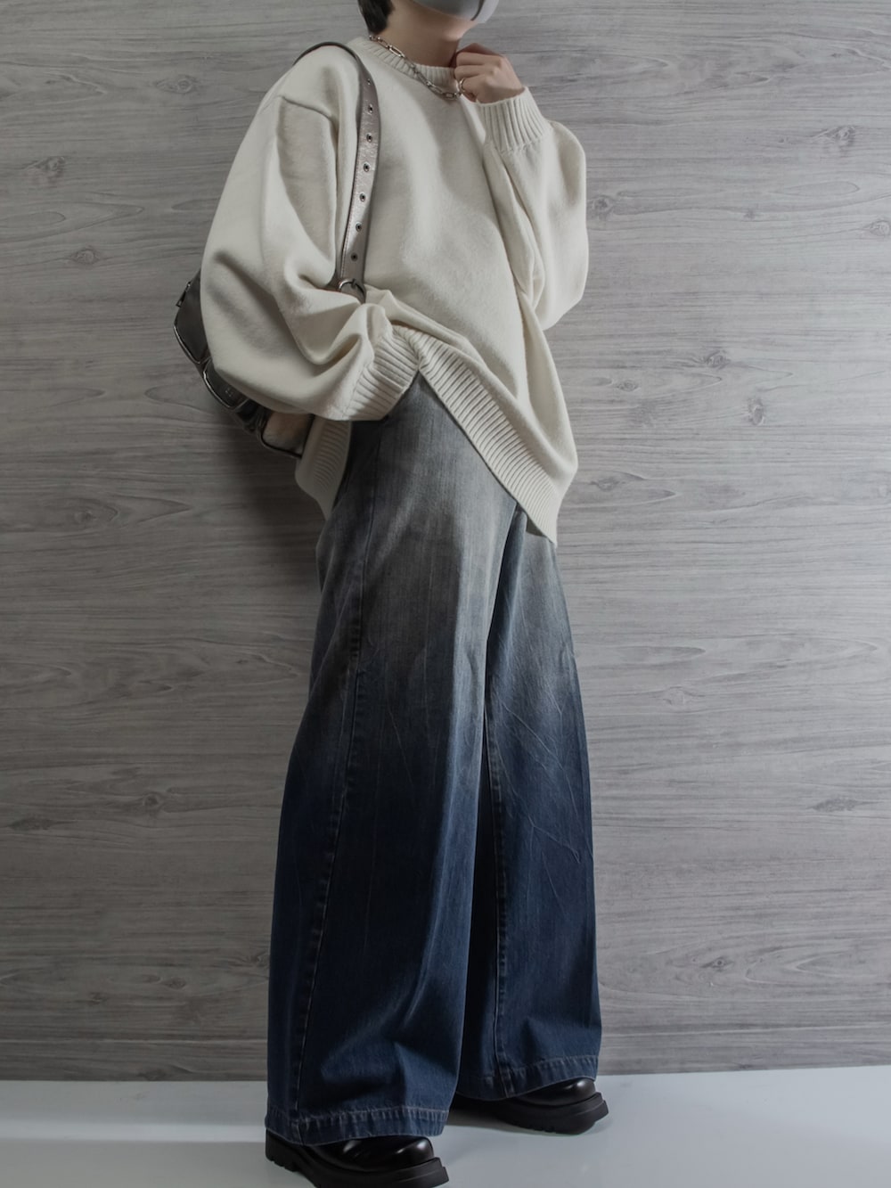 ブラック系のダウンジャケット/コート、ホワイト系のニット/セーター、ブルー系のデニムパンツを着用したメンズの冬コーディネートの2枚目の写真