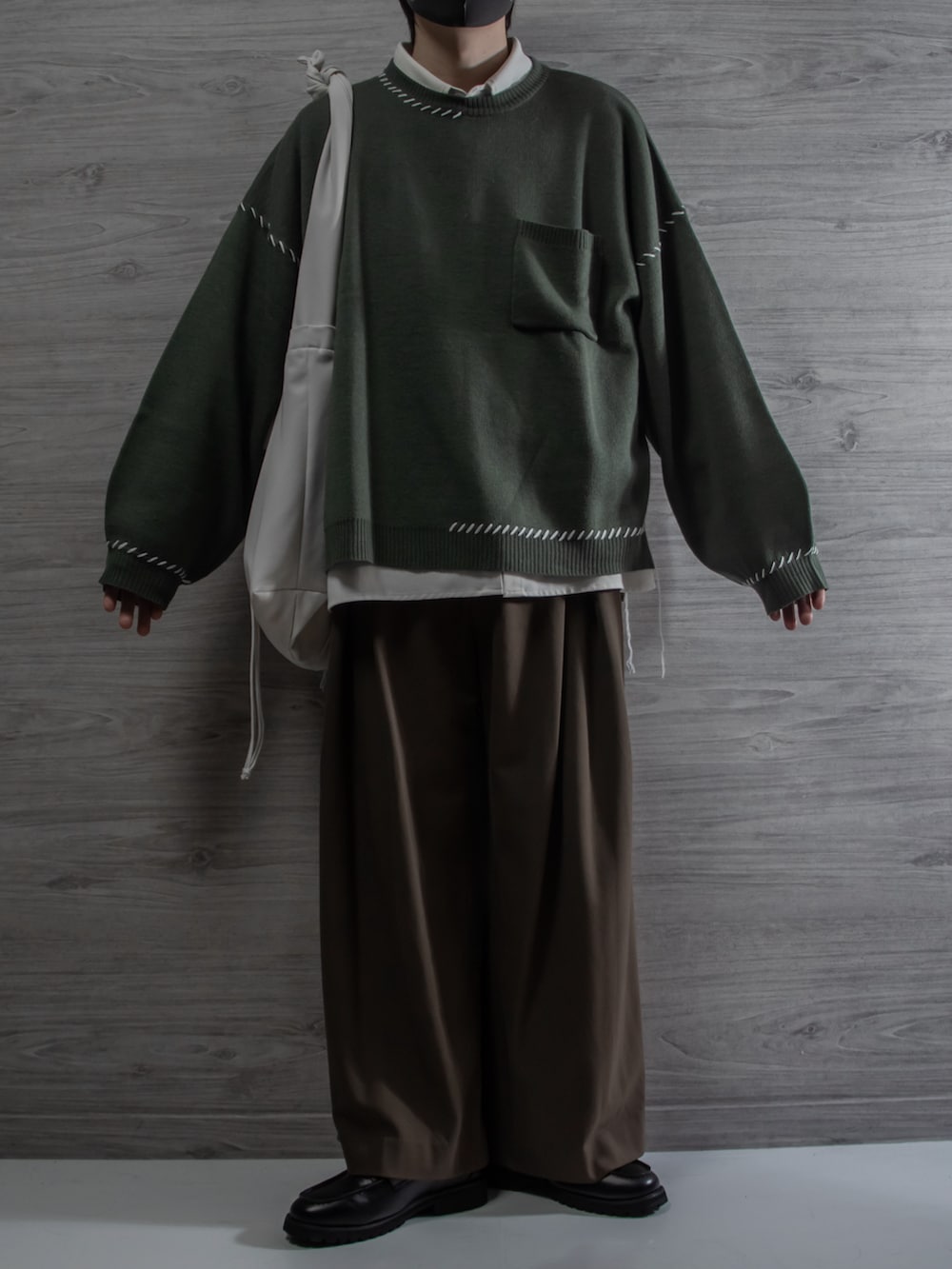 グリーン系のニット/セーター、ホワイト系のシャツ/ブラウス、ブラウン系のスラックスを着用したメンズの冬コーディネートの2枚目の写真