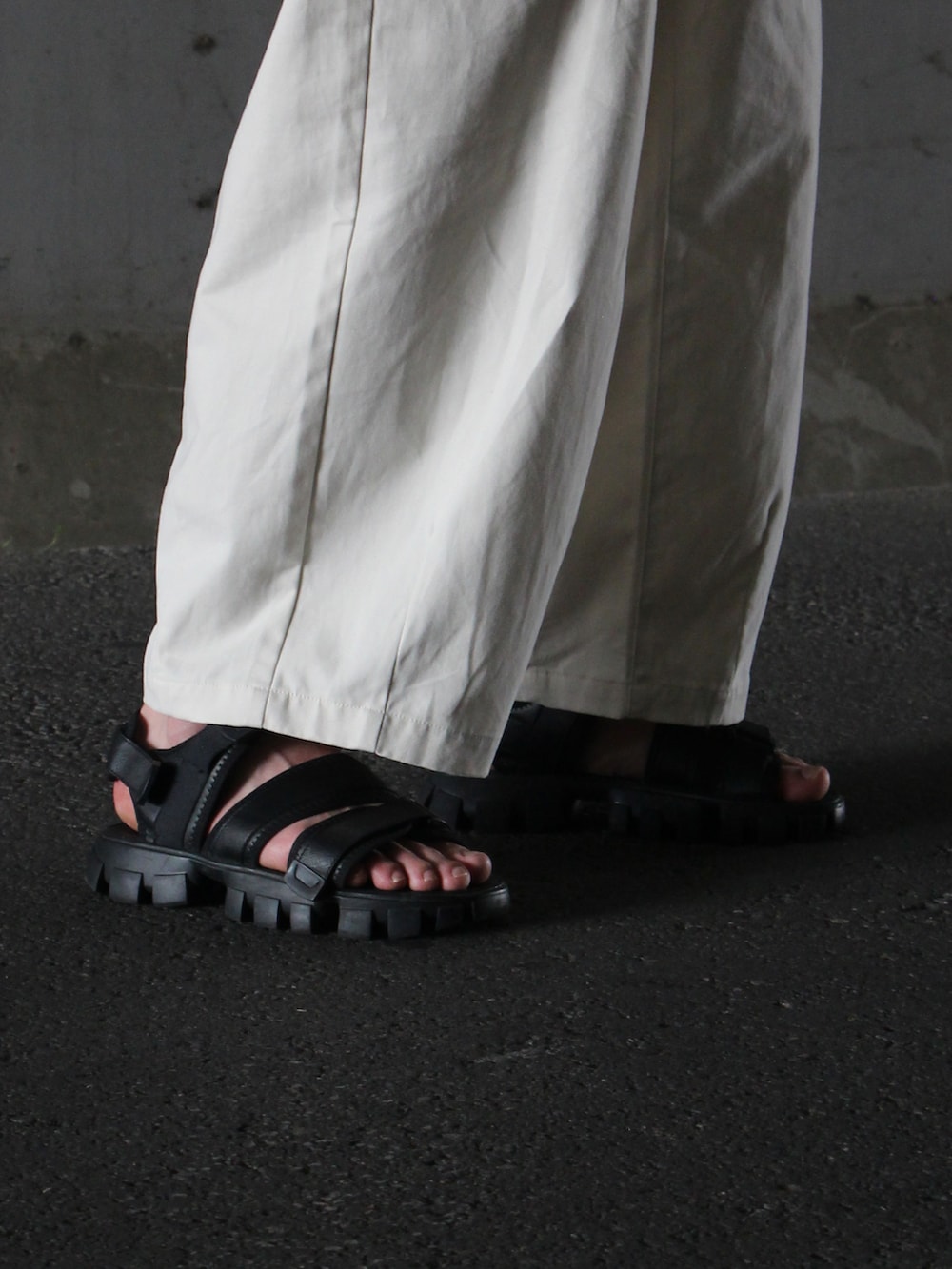 ブラック系のTシャツ/カットソー、ベージュ系のチノパンツ、ブラック系のサンダルを着用したメンズの夏コーディネートの4枚目の写真