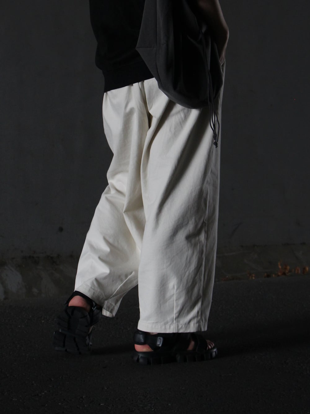 ブラック系のTシャツ/カットソー、ベージュ系のチノパンツ、ブラック系のサンダルを着用したメンズの夏コーディネートの3枚目の写真