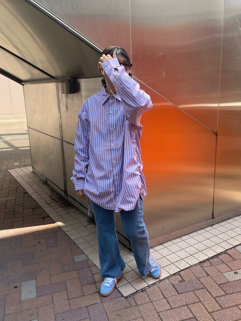 ブルー系のデニムパンツ、パープル系のシャツ/ブラウス、ブルー系のスニーカーを着用したレディースの秋コーディネートの3枚目の写真