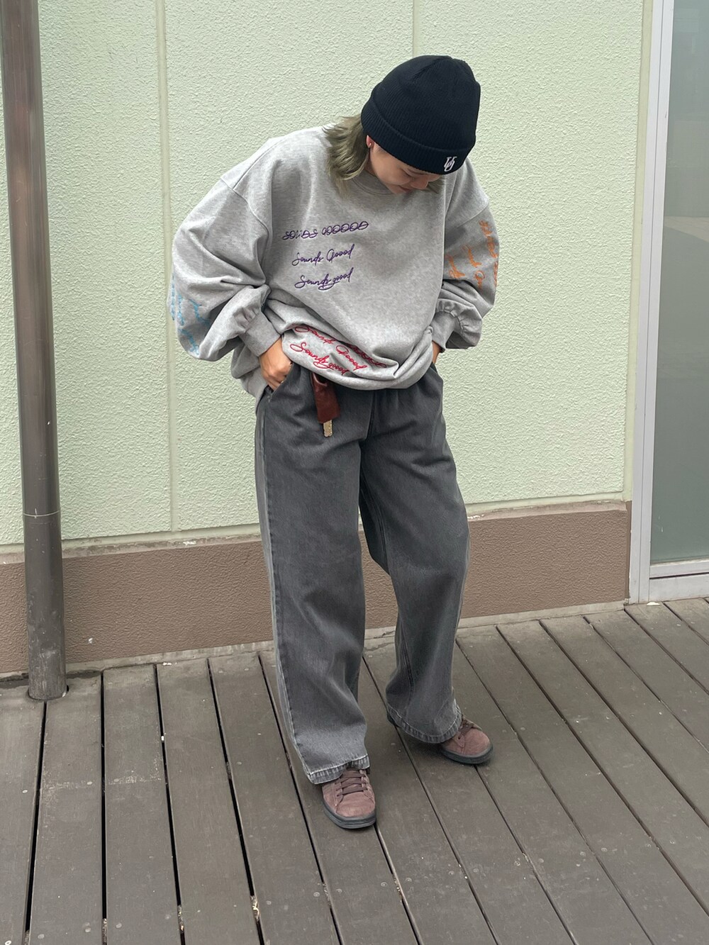 ブラック系のデニムパンツ、グレー系のスウェット、ブラウン系のスニーカーを着用したレディースの秋コーディネートの2枚目の写真