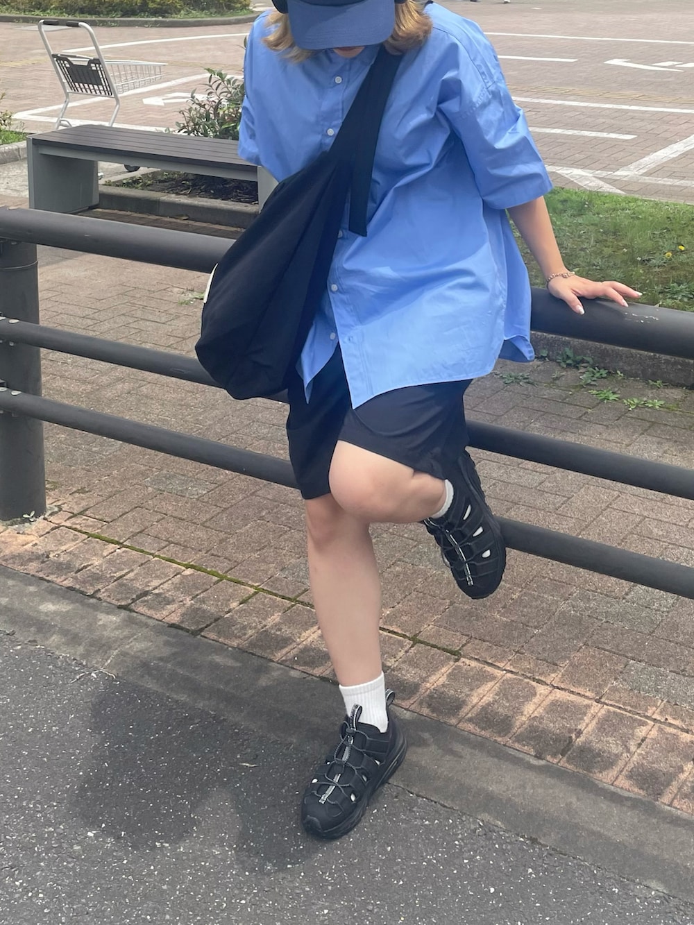 ブラック系のスニーカー、ブラック系のショルダーバッグ、ブルー系のシャツ/ブラウスを着用したレディースの夏コーディネートの2枚目の写真