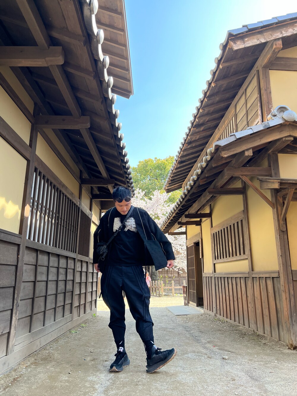 ブラック系のバッグ、ブラック系のその他アウター、ブラック系のTシャツ/カットソーを着用したメンズの夏コーディネートの2枚目の写真