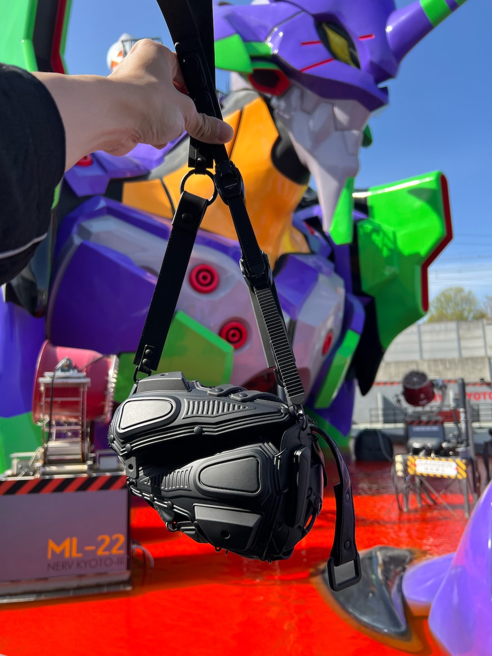 ブラック系のバッグ、ブラック系のその他アウター、ブラック系のTシャツ/カットソーを着用したメンズの夏コーディネートの5枚目の写真