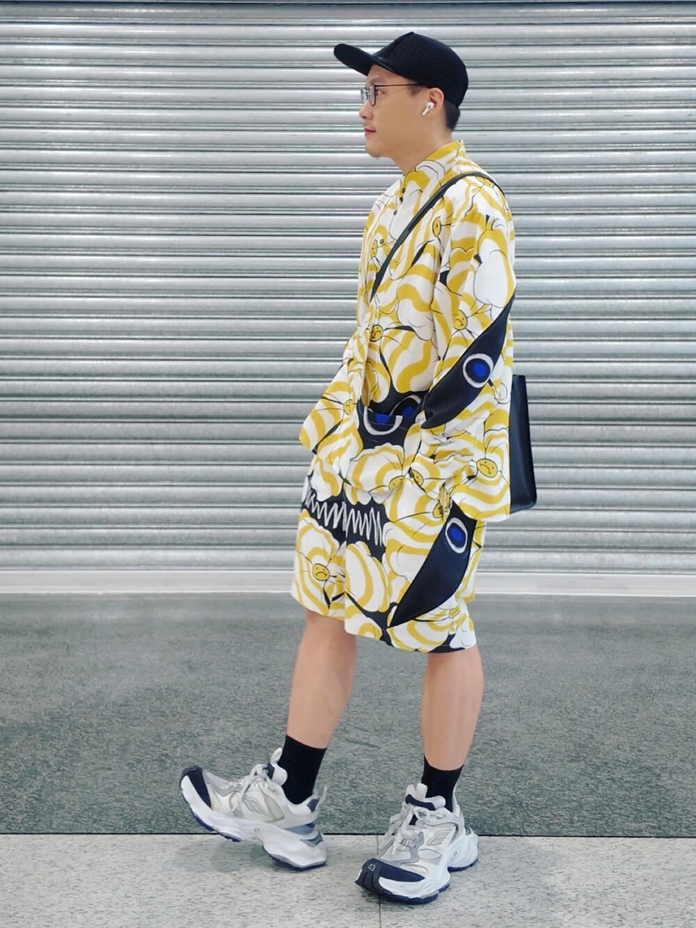 イエロー系のトップス、ホワイト系のシューズ、ブラック系のキャップを着用したメンズの夏コーディネートの2枚目の写真