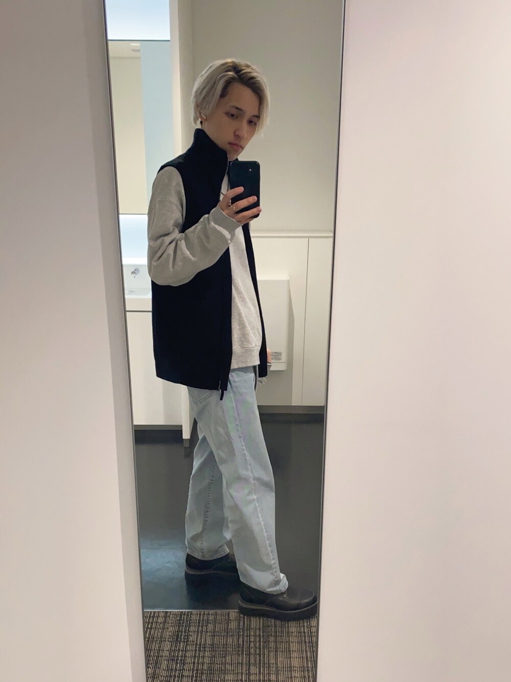 グレー系のスウェット、ブラック系のベスト、ブルー系のデニムパンツを着用したメンズの春コーディネートの2枚目の写真