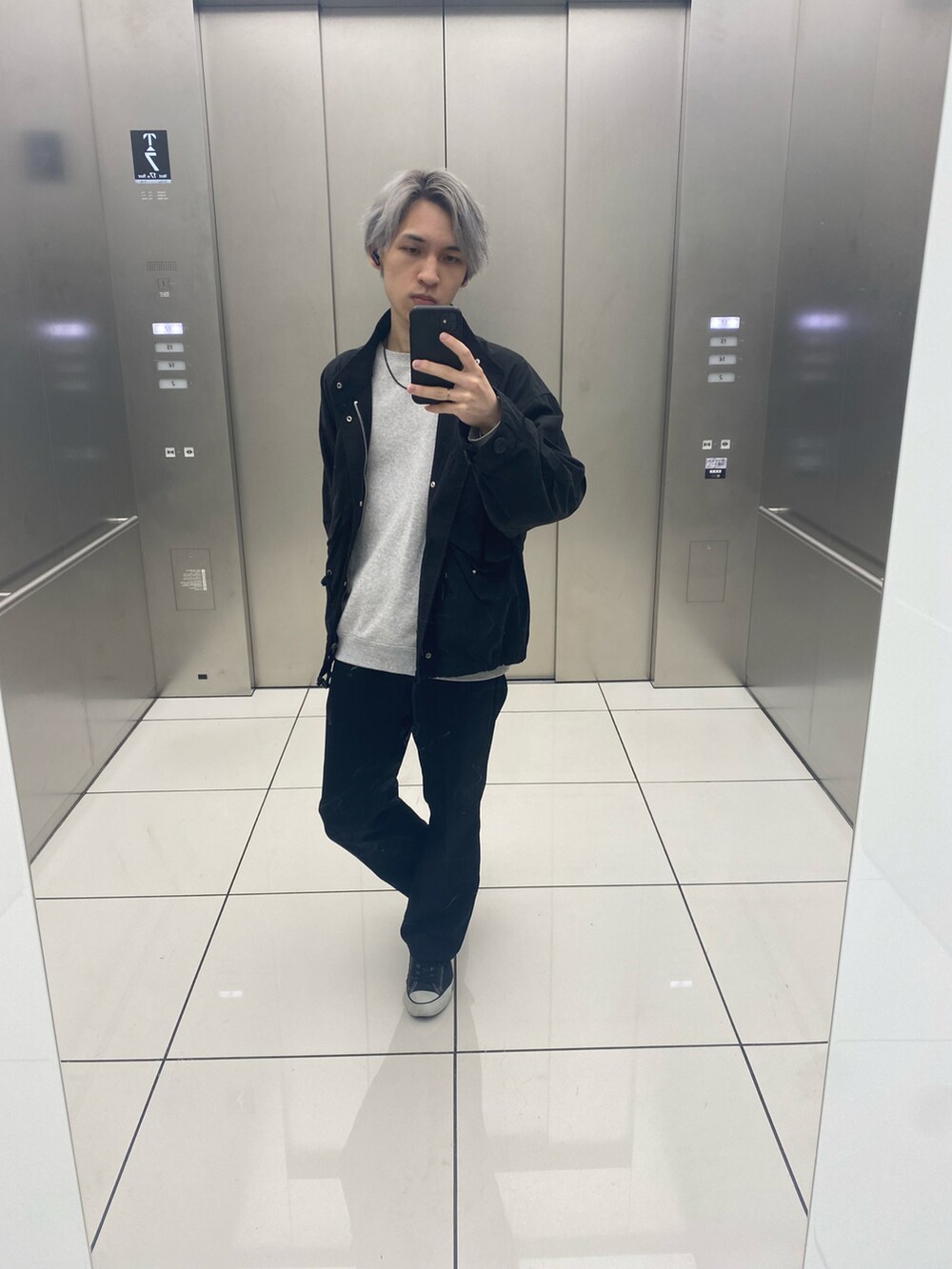 グレー系のスウェット、ブラック系のスラックス、ブラック系のスニーカーを着用したメンズの春コーディネートの2枚目の写真