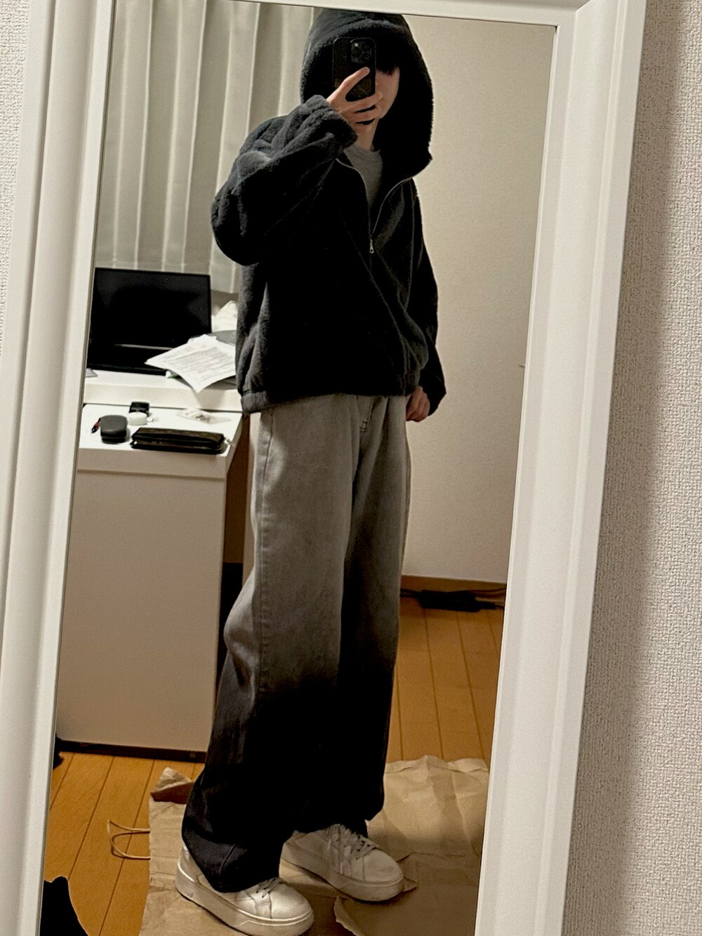 ブラック系のデニムパンツ、ホワイト系のスニーカー、グレー系のパーカーを着用したメンズの秋コーディネートの2枚目の写真
