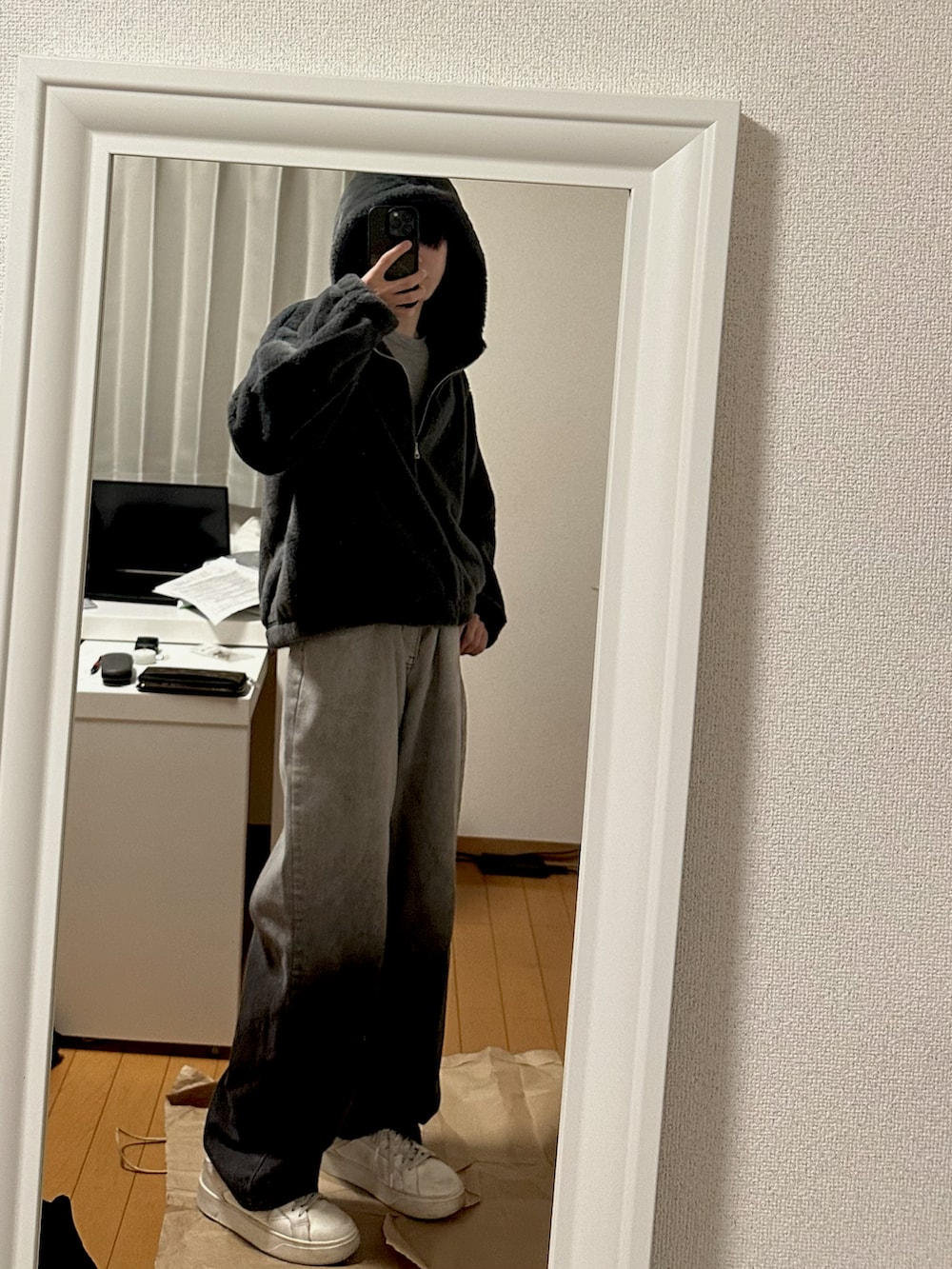 ホワイト系のスニーカー、ブラック系のデニムパンツ、グレー系のパーカーを着用したメンズの秋コーディネートの2枚目の写真