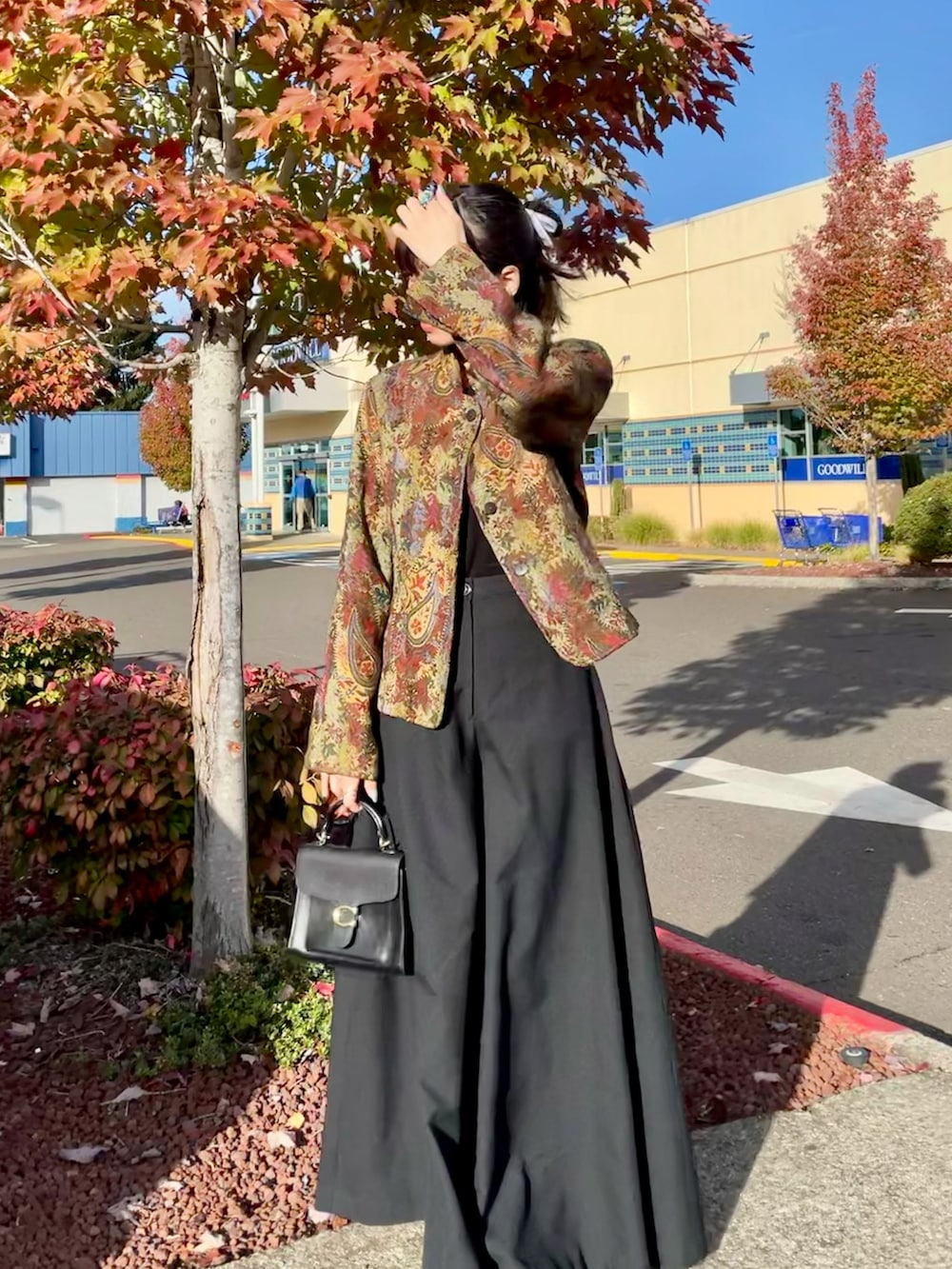 ブラック系のハンドバッグ、ブラック系のパンツ、ベージュ系のテーラードジャケットを着用したレディースの秋コーディネートの2枚目の写真