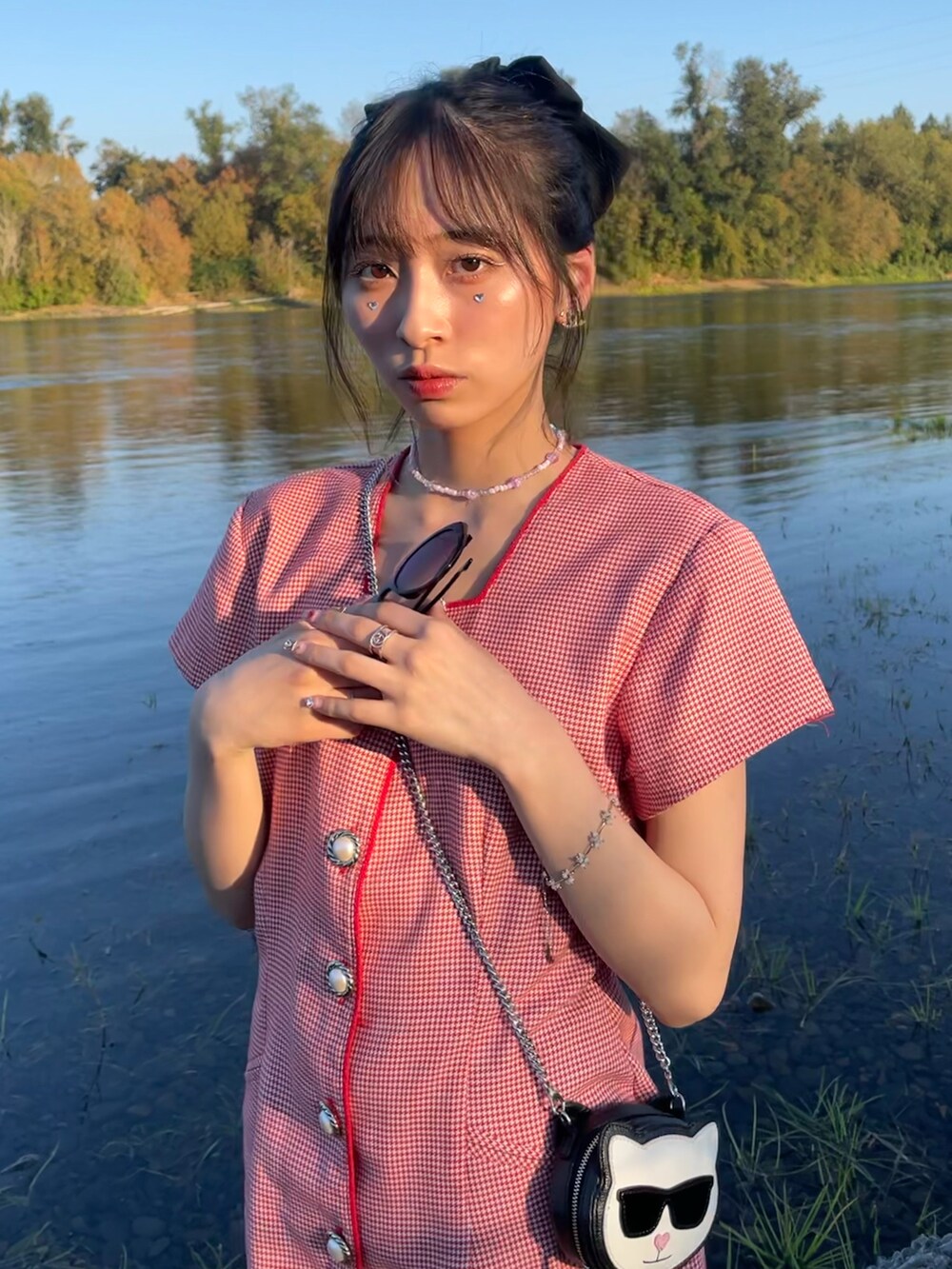 レッド系のワンピース、ブラック系のショルダーバッグ、ホワイト系のパンプスを着用したレディースの秋コーディネートの2枚目の写真