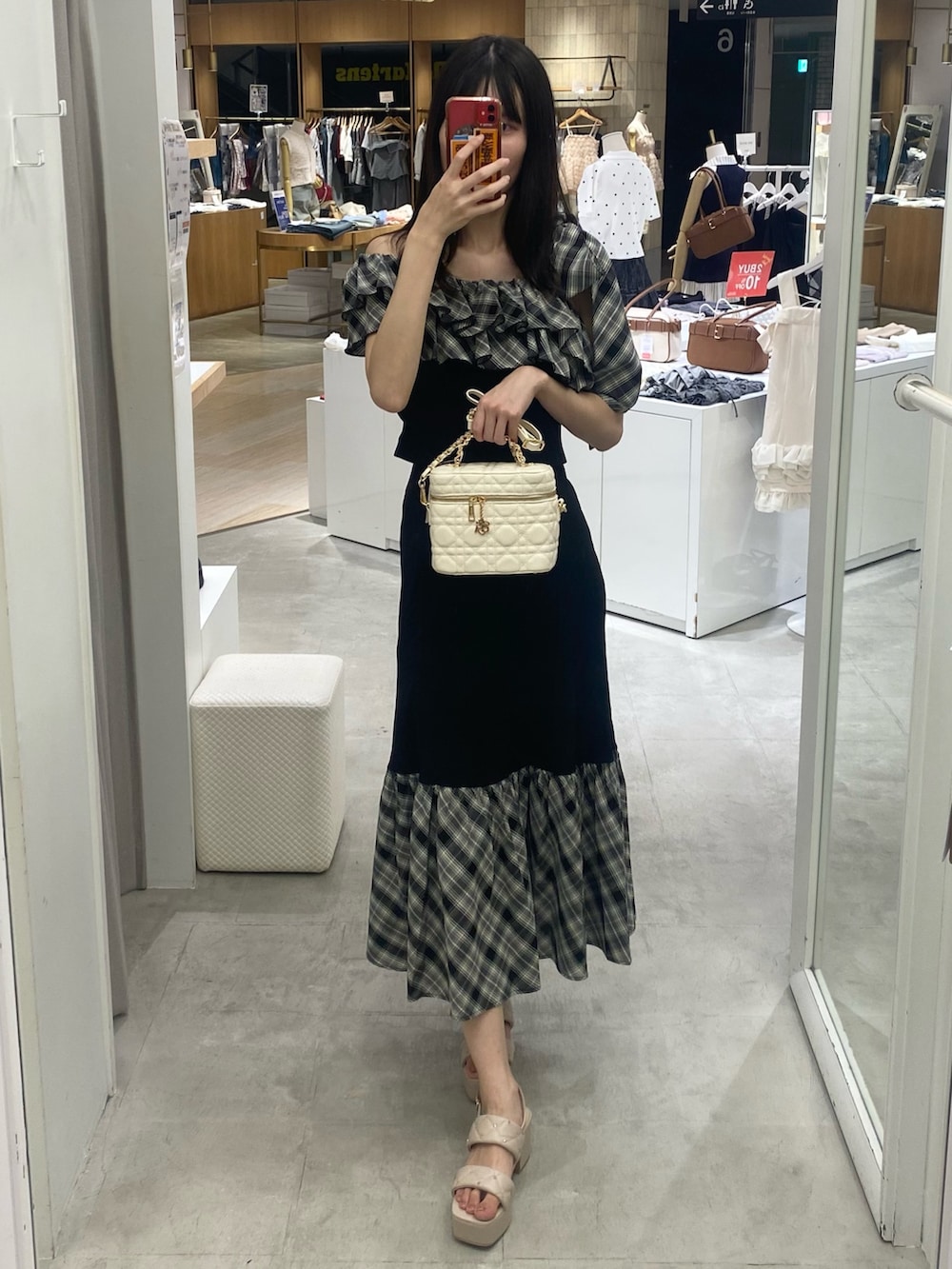 ブラック系のスカート、ホワイト系のショルダーバッグ、ベージュ系のサンダルを着用したレディースの秋コーディネートの5枚目の写真